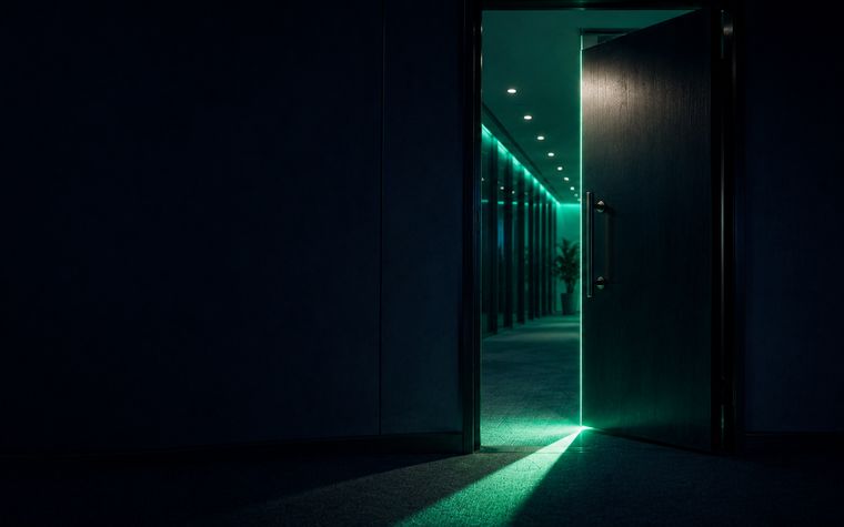 A door held open, light spilling into a dark corridor